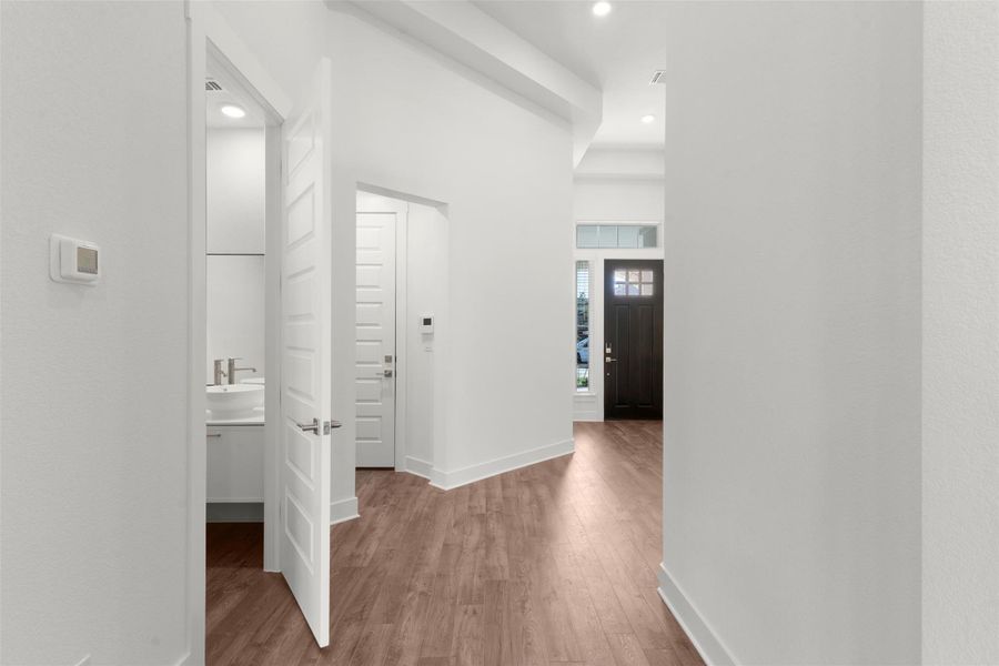 Hall with wood finished floors and recessed lighting