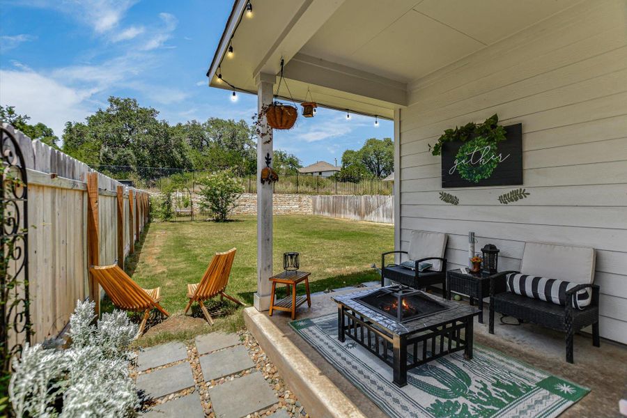 An inviting covered patio with a fire pit offers a serene outdoor gathering space next to a generous fenced yard. An inviting covered patio with a fire pit offers a serene outdoor gathering space next to a generous fenced yard.