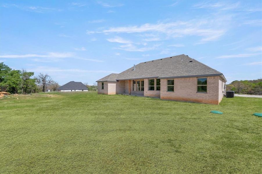 Back of property featuring central AC unit and a lawn