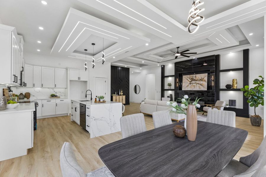 Gleaming wood floors anchor an open floorplan showcasing intricate, modern tray ceilings.
