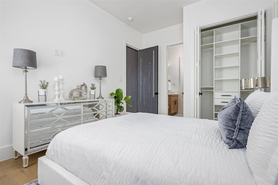 A spacious downstairs secondary bedroom with a custom closet is paired with a luxe full bath, ideal for guests or multi-generational living A spacious downstairs secondary bedroom with a custom closet is paired with a luxe full bath, ideal for guests or multi-generational living