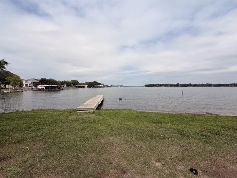 Waterfront property featuring a private day dock and a grassy shoreline