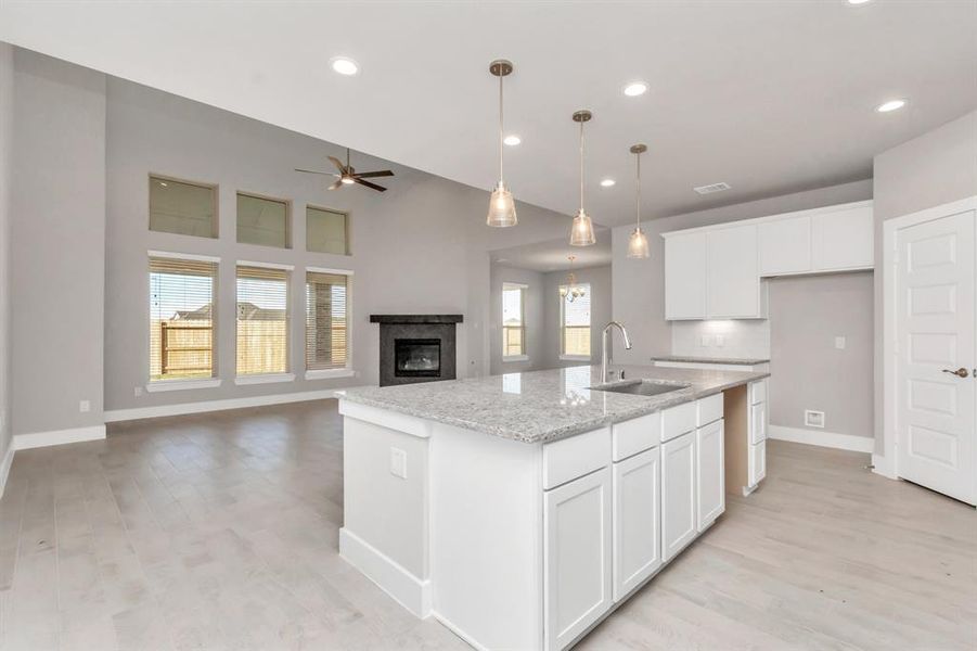 This generously spacious kitchen is a dream realized! With a massive granite island, high ceilings, soft close cabinets, granite countertops, stainless steel appliances, a sleek tile backsplash, recessed lighting, and an extended counter area, it offers both style and practicality. All this opens up to the expansive family room, creating a perfect hub for gatherings. Sample photo of completed home with similar floor plan. As-built interior colors and selections may vary.