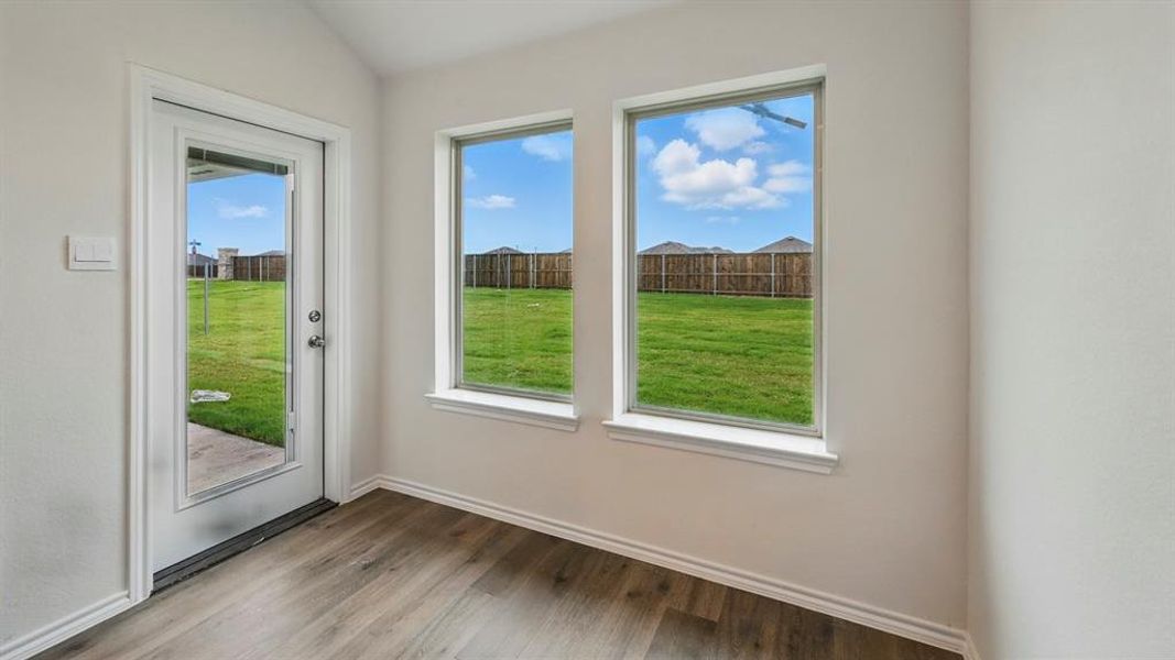 Doorway featuring wood finished floors and vaulted ceiling