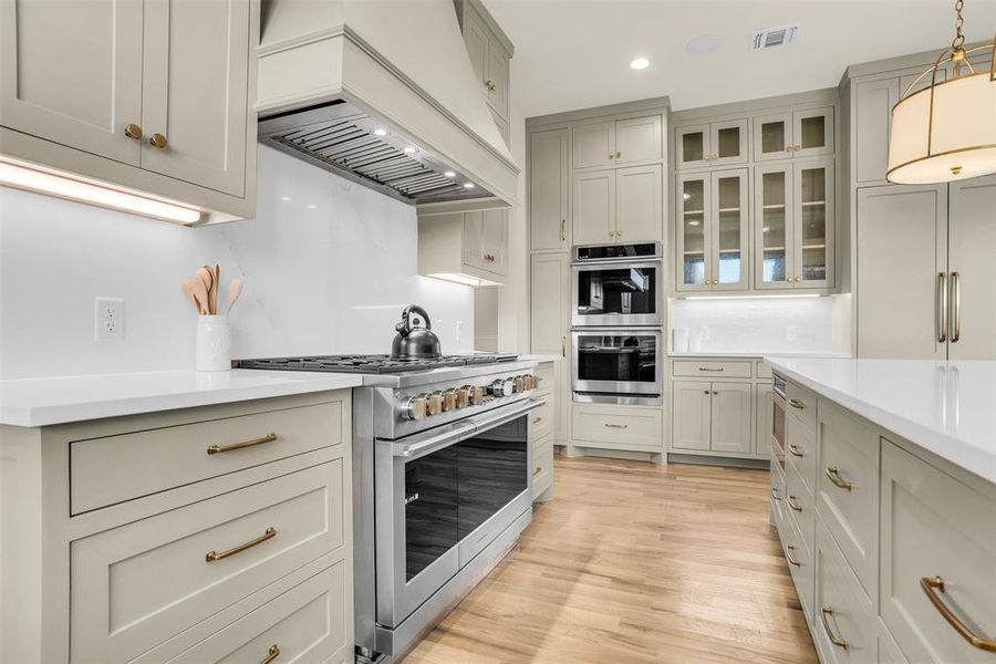 Kitchen with premium range hood, high quality appliances, pendant lighting, recessed lighting, and light stone countertops