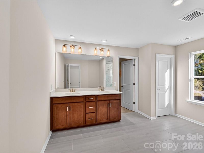 Primary En Suite Bath with Modern Wood-Toned Cabinetry and Dual Vanity. Primary En Suite Bath with Modern Wood-Toned Cabinetry and Dual Vanity.