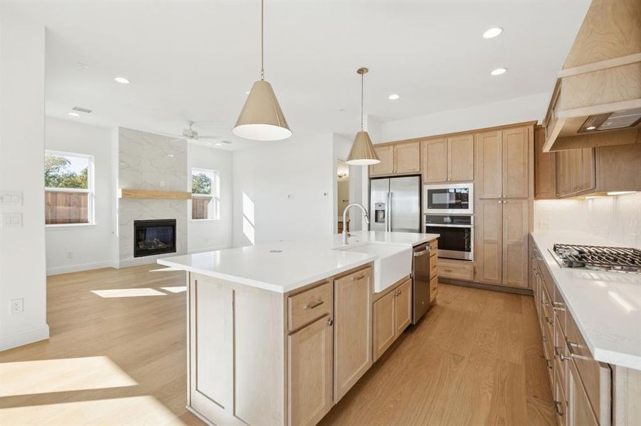 Kitchen with light countertops, decorative backsplash, a kitchen island with sink, pendant lighting, and recessed lighting