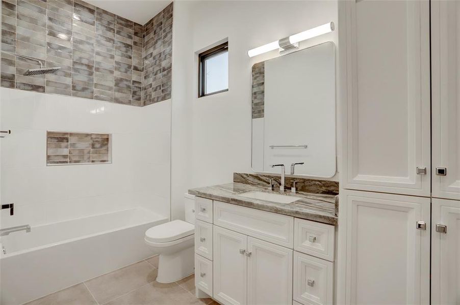 BATH #5: Tub shower combination with Unique tile details coordinating with Tempest Blue stone.  This access is the bath for the fifth bedroom flex room also Public bath for the game room.