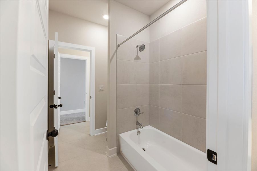 Bathroom featuring bathing tub / shower combination and light tile patterned floors