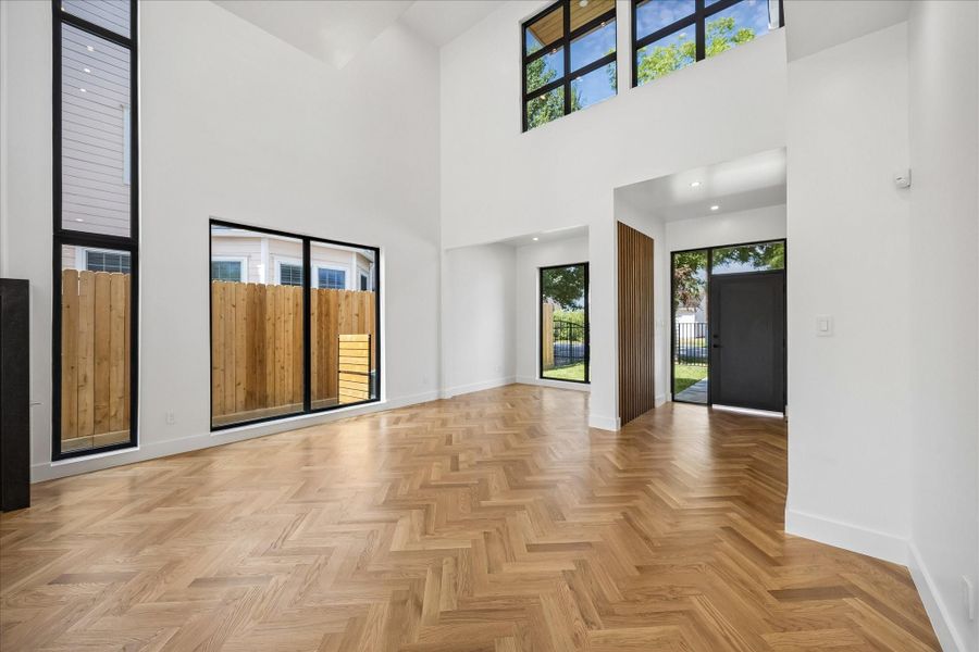 Stunning open-concept living area with high ceilings, herringbone white oak hard wood floors, and large windows that flood the space with natural light. Stunning open-concept living area with high ceilings, herringbone white oak hard wood floors, and large windows that flood the space with natural light.