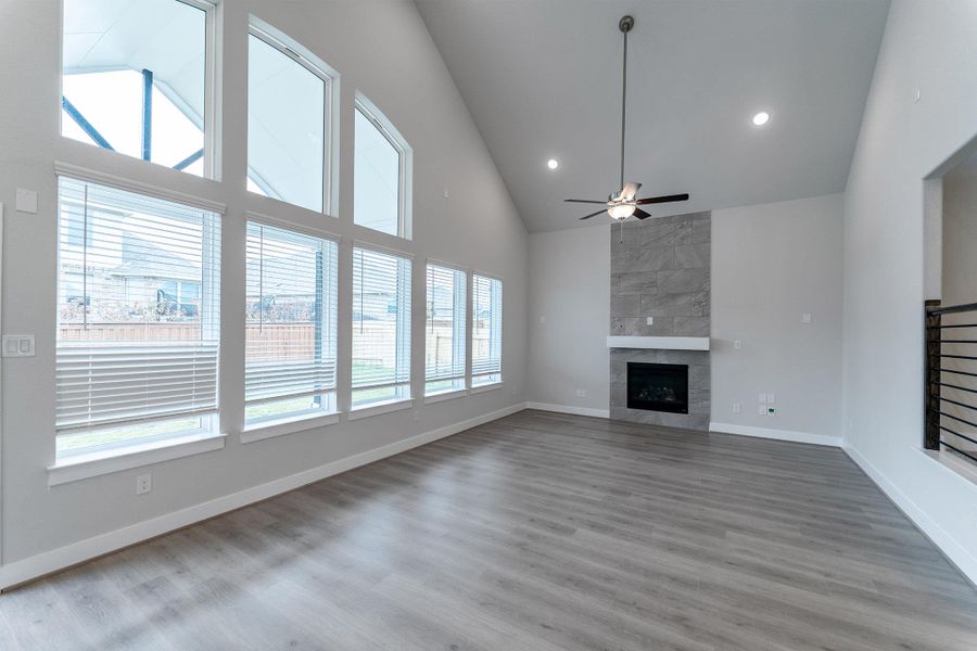 Unfurnished living room featuring vaulted ceiling, ceiling fan, a high end fireplace, light wood-type flooring, and recessed lighting