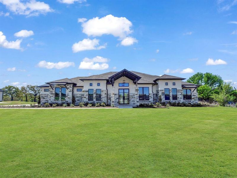 Rear view of property with a yard, french doors, stone siding, and stucco siding Rear view of property with a yard, french doors, stone siding, and stucco siding