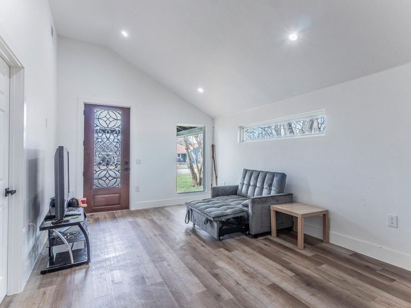 Living area featuring vaulted ceiling, light wood-style flooring, and recessed lighting