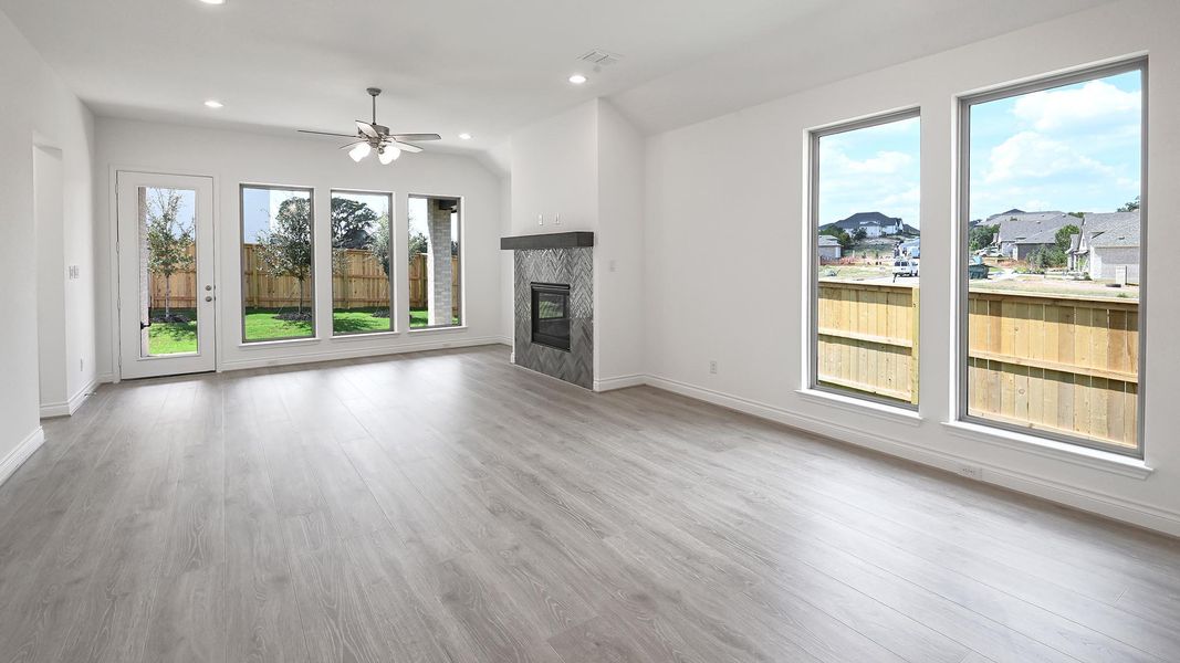 Unfurnished living room featuring light wood-type flooring, recessed lighting, vaulted ceiling, ceiling fan, and a glass covered fireplace Unfurnished living room featuring light wood-type flooring, recessed lighting, vaulted ceiling, ceiling fan, and a glass covered fireplace