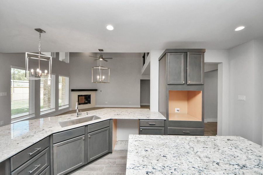 This kitchen is truly a chef's dream! This haven Boasts high ceilings, recessed & pendant lighting, stained wood cabinets, granite countertops, stainless steel appliances, a modern tile backsplash.  All of this overlooks your expansive family room, creating a perfect space for culinary delights and family gatherings.