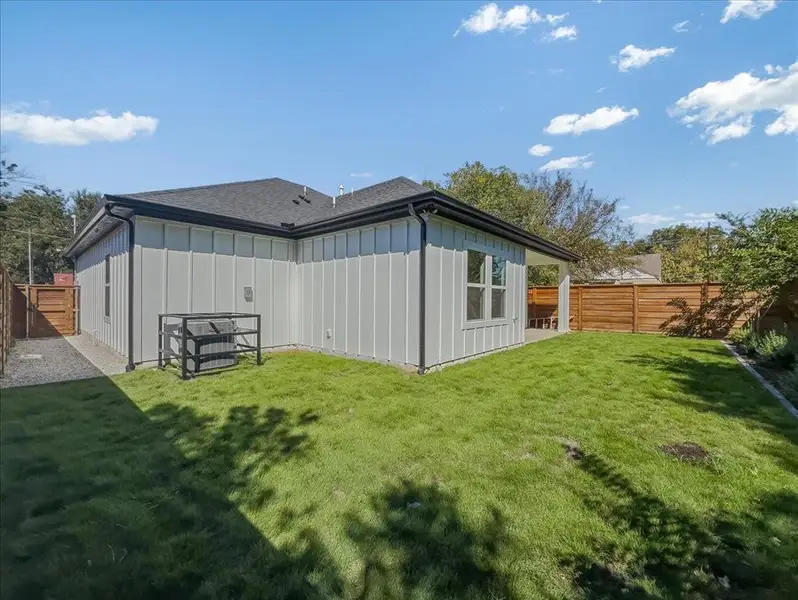 Back of house with board and batten siding, a fenced backyard, and a shingled roof Back of house with board and batten siding, a fenced backyard, and a shingled roof