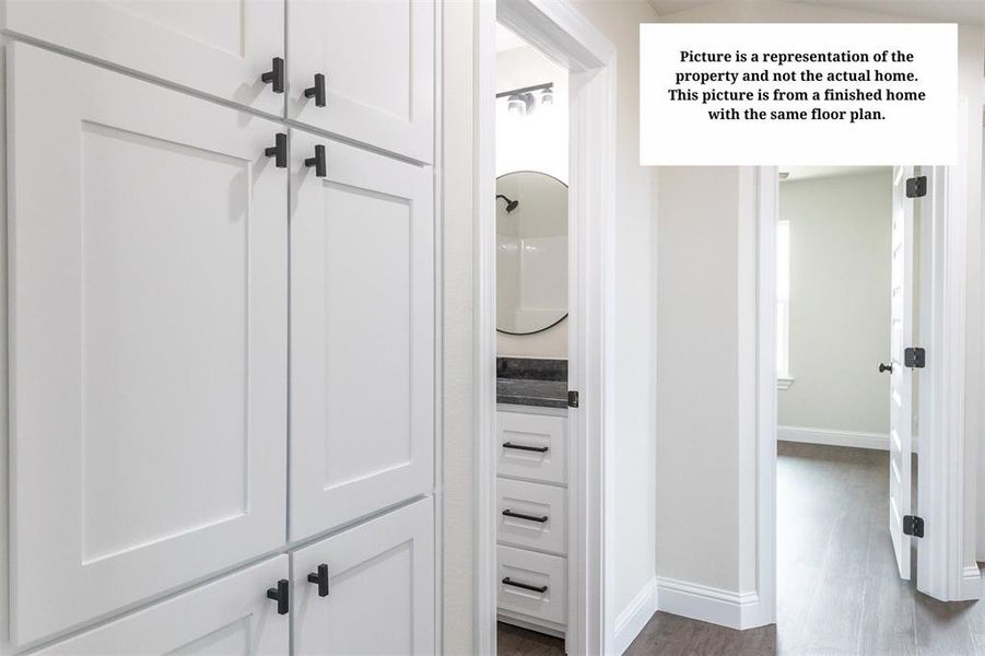 White shaker-style cabinetry with matte black hardware, featuring a built-in vanity with a dark stone-finish countertop and a circular mirror