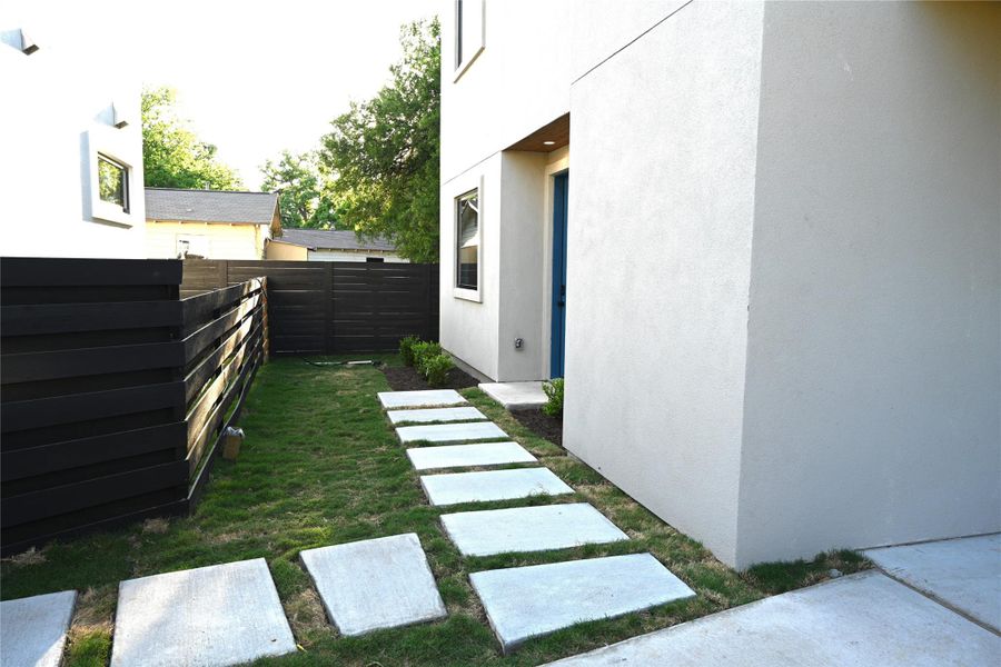 The property features a walkway of square stepping stones set in a lawn, leading to entrance door