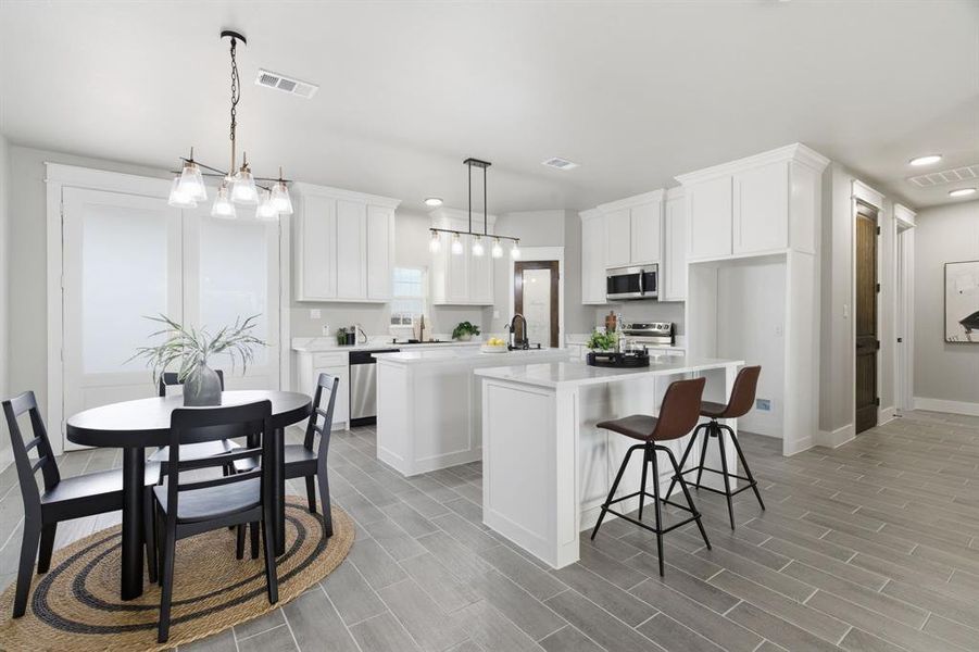 Kitchen with a breakfast bar area, hanging light fixtures, white cabinets, appliances with stainless steel finishes, and recessed lighting