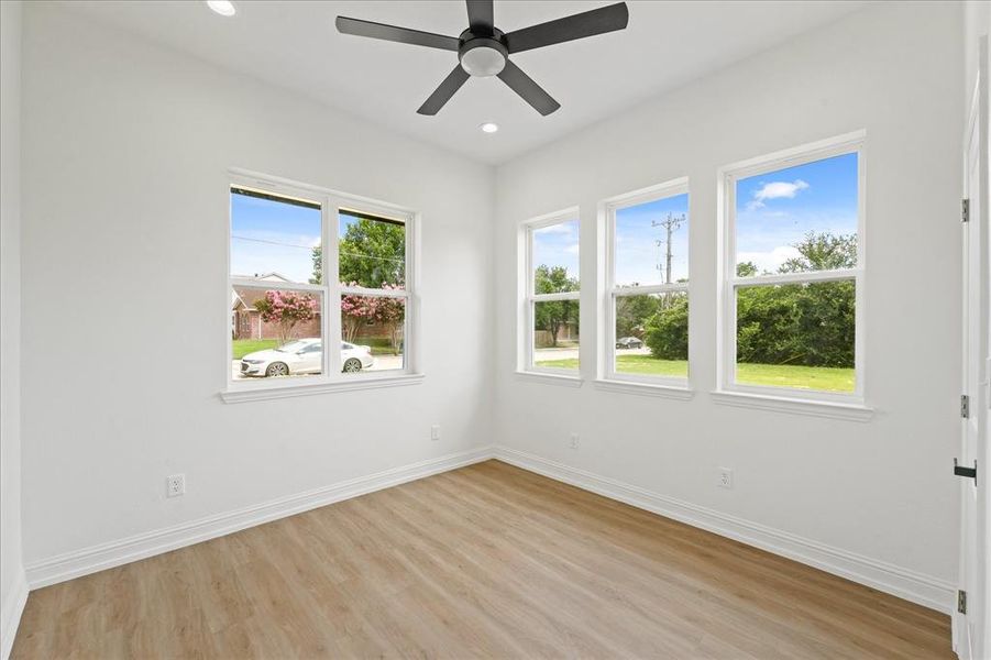 Bright interior space featuring wood-finish flooring, a contemporary ceiling fan, recessed lighting, and multiple windows with white trim