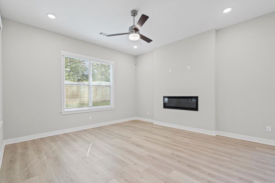 Unfurnished living room with light wood-style flooring, a glass covered fireplace, recessed lighting, and ceiling fan