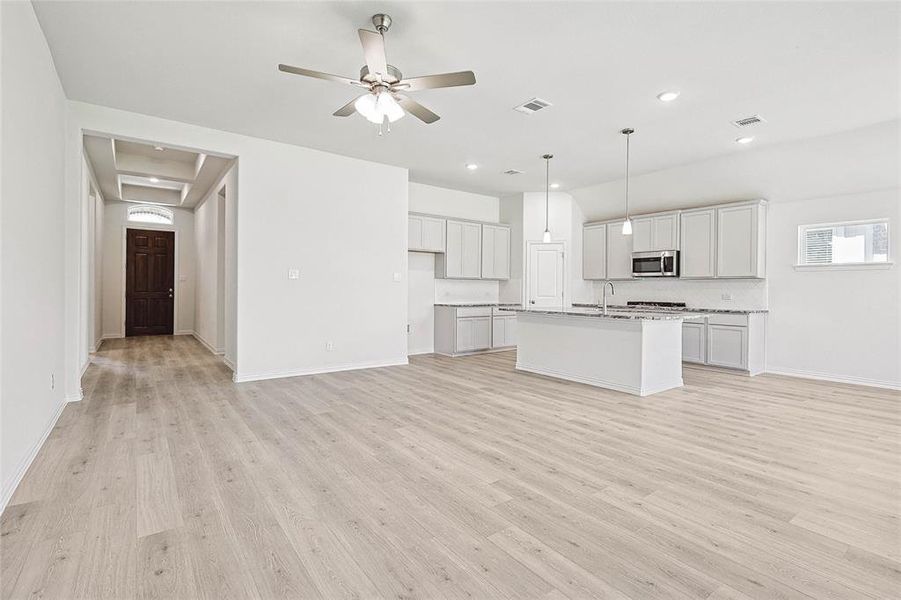 Unfurnished living room with ceiling fan, light wood-type flooring, and sink