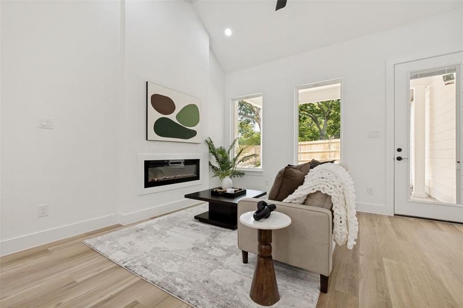 Living area featuring a vaulted ceiling and light wood-finish flooring Living area featuring a vaulted ceiling and light wood-finish flooring