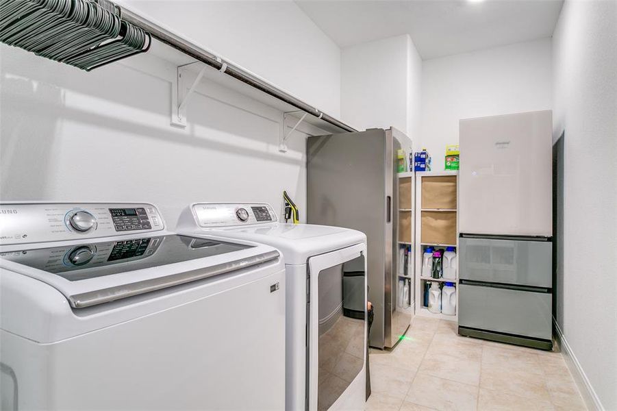Washroom with light tile patterned flooring and washer and dryer