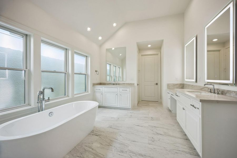 Behold the primary bath, which features a freestanding soaking tub, dual vanities and abundant natural light.