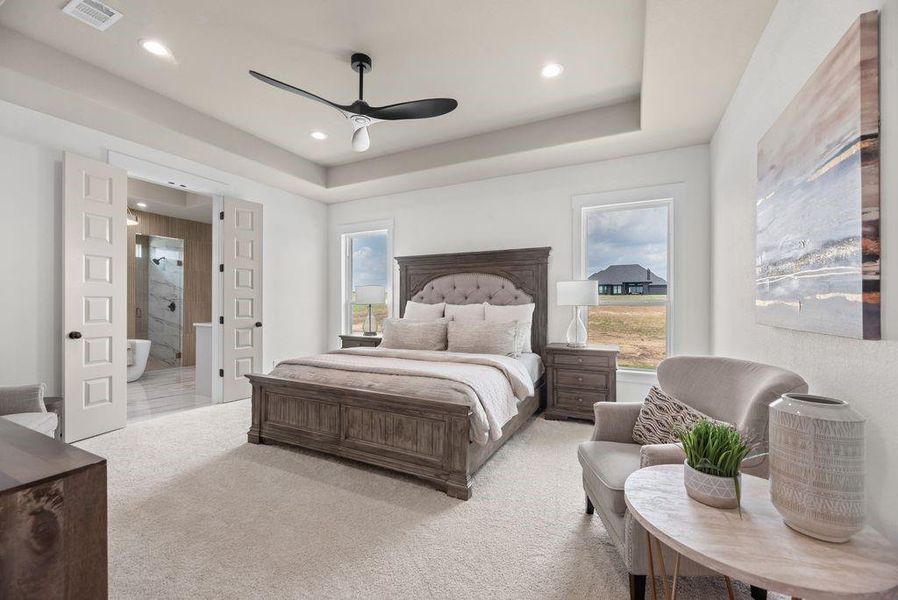 Carpeted bedroom with a raised ceiling, ceiling fan, connected bathroom, and recessed lighting Carpeted bedroom with a raised ceiling, ceiling fan, connected bathroom, and recessed lighting