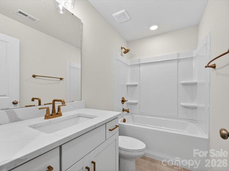 Hall bath vanity with quartz countertops with soft close drawers & cabinets. Tiled bathroom floors and deep soak tub.