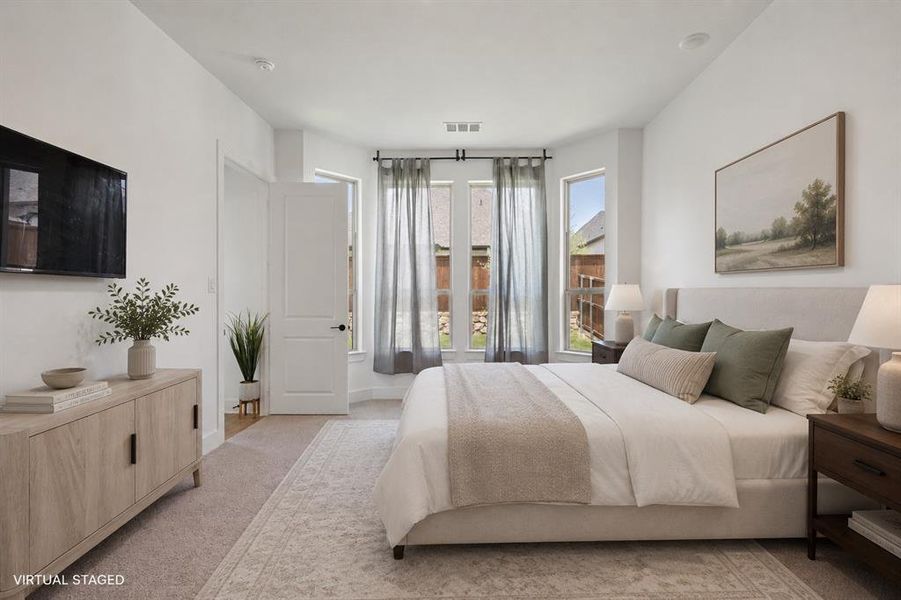 Carpeted bedroom featuring a large bay window, light wood-finish flooring, a white paneled door, and ample natural light Carpeted bedroom featuring a large bay window, light wood-finish flooring, a white paneled door, and ample natural light
