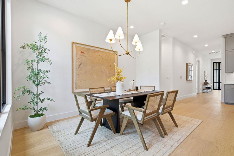 Smooth wood floors and recessed lighting enhance this airy dining area with tall white walls.