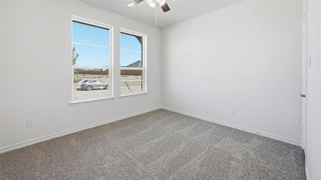 Spacious room featuring neutral carpeting, light-toned walls, and a ceiling fan Spacious room featuring neutral carpeting, light-toned walls, and a ceiling fan