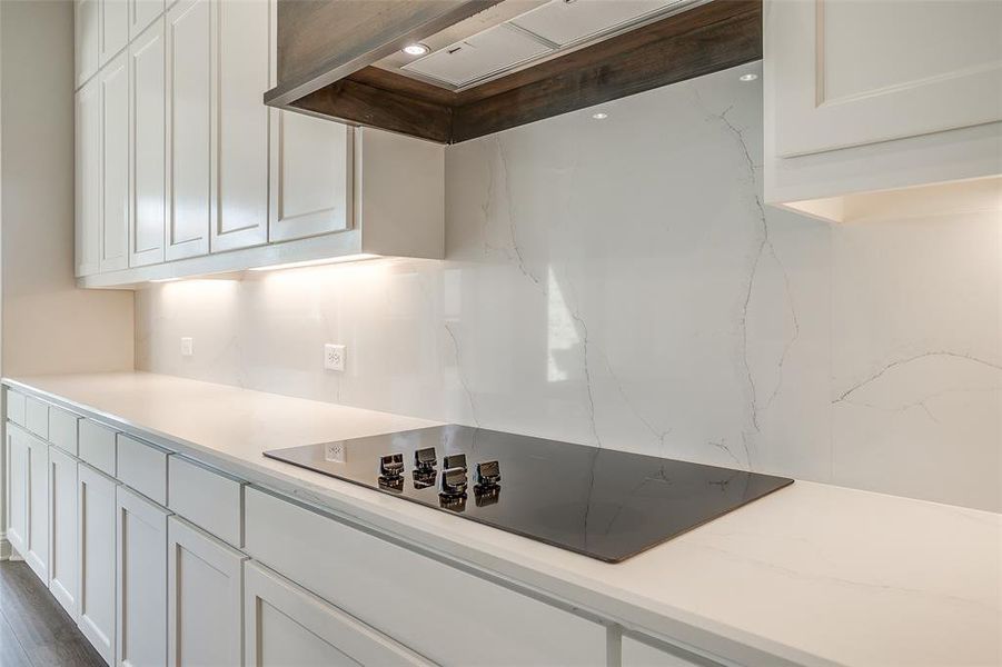 Kitchen featuring exhaust hood, black electric cooktop, hardwood / wood-style floors, and white cabinets