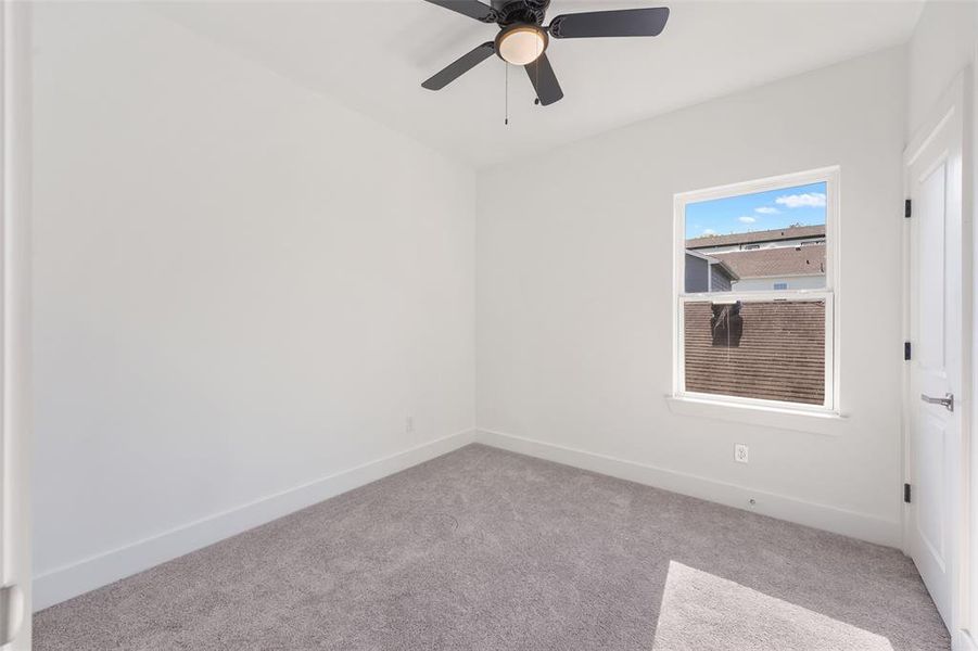 Carpeted spare room featuring baseboards and a ceiling fan
