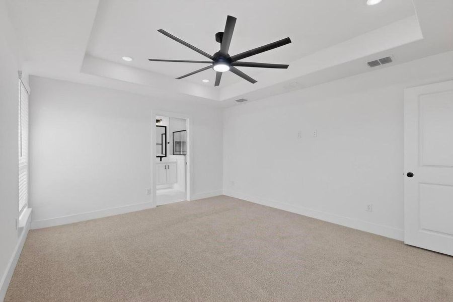 Unfurnished room with recessed lighting, light colored carpet, ceiling fan, and a tray ceiling