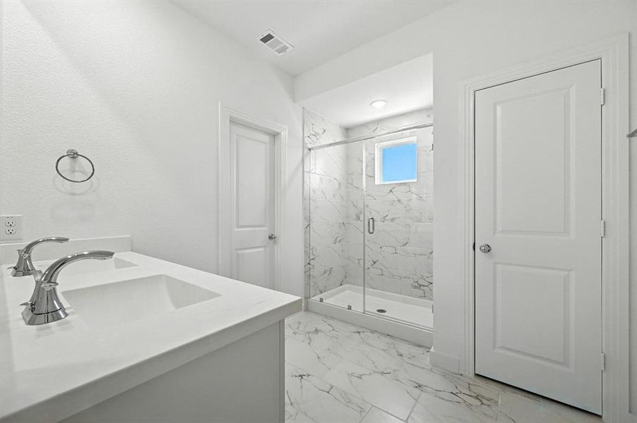 Full bathroom featuring a marble finish shower, vanity, and light marble finish flooring