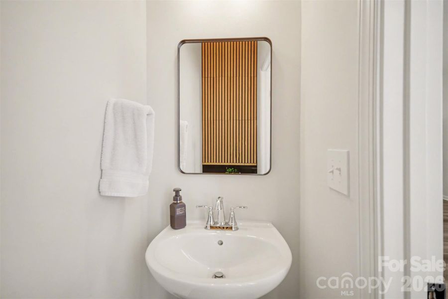 Half bath with modern pedestal sink & warm wood accent wall