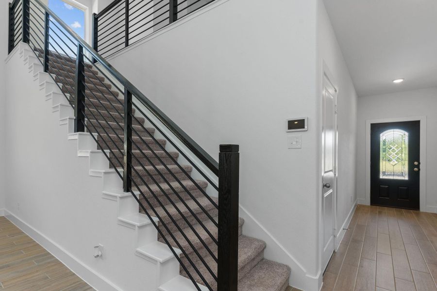 The dramatic two-story entry features a striking modern cable iron staircase, anchored by soaring ceilings and expansive windows that flood the space with natural light. A stunning welcome to your new home! The dramatic two-story entry features a striking modern cable iron staircase, anchored by soaring ceilings and expansive windows that flood the space with natural light. A stunning welcome to your new home!