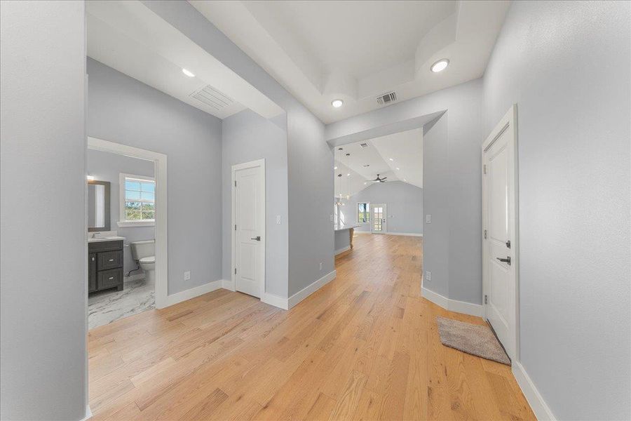 Hallway with light wood-style floors, recessed lighting, and vaulted ceiling Hallway with light wood-style floors, recessed lighting, and vaulted ceiling