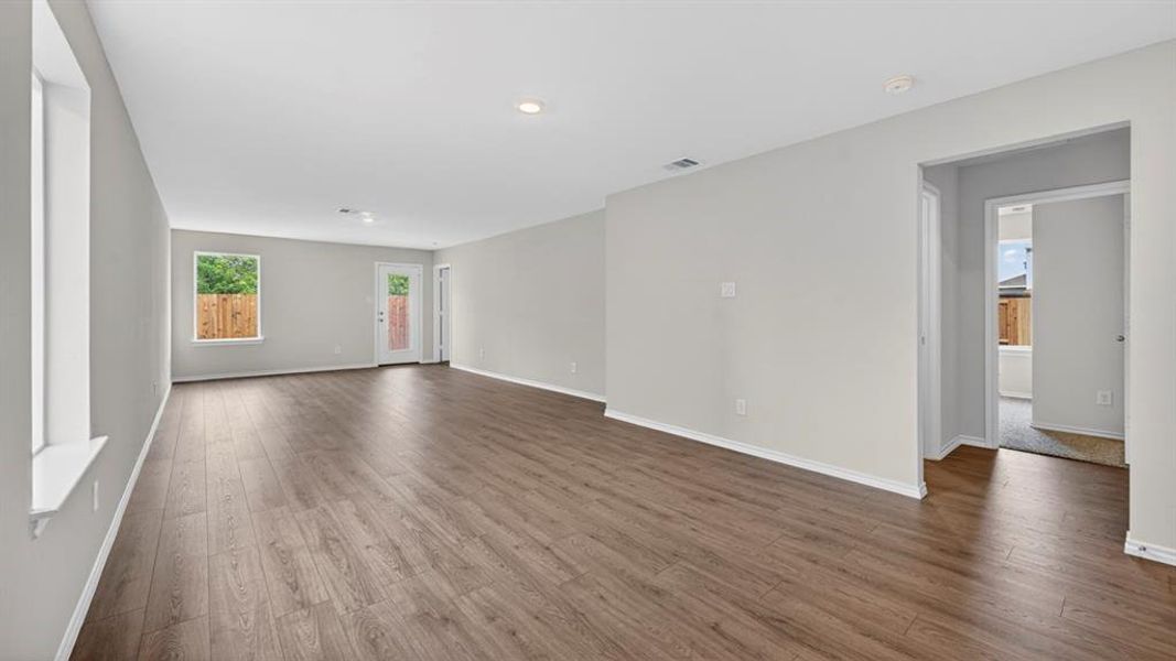 Spacious living area featuring wood-finish flooring, neutral wall tones, recessed lighting, and white baseboards