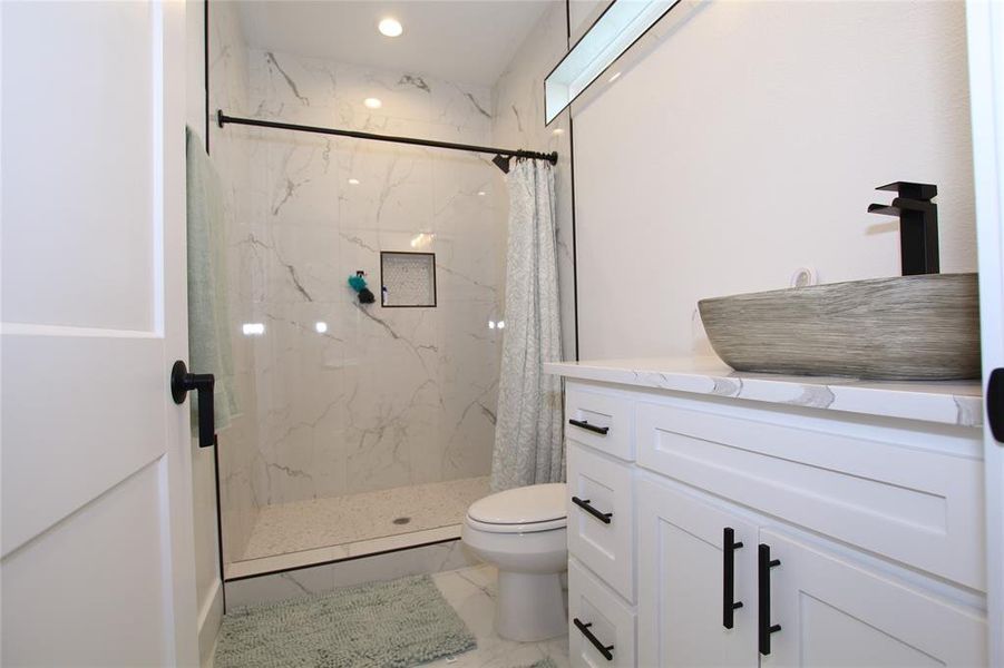 Full bath featuring vanity, a marble finish shower, and light marble finish floors Full bath featuring vanity, a marble finish shower, and light marble finish floors