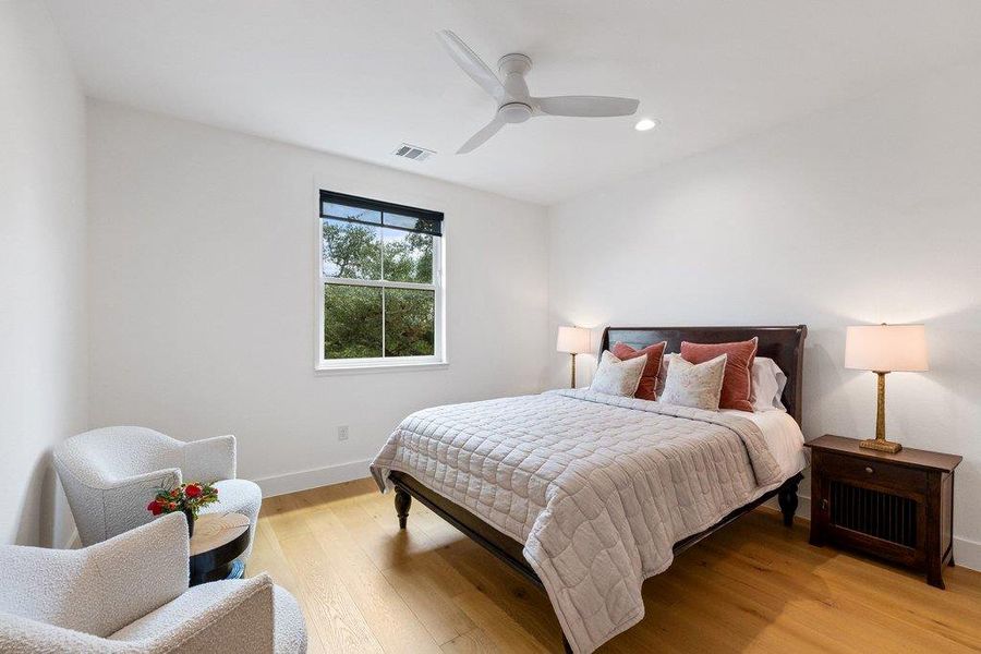A tranquil bedroom with warm hardwood flooring and a refreshing ceiling fan for ultimate comfort. A tranquil bedroom with warm hardwood flooring and a refreshing ceiling fan for ultimate comfort.
