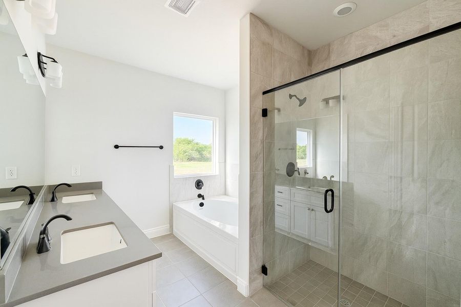 Primary Bath with separate tub/shower and double undermount sinks. Quartz countertops and tile to the ceiling! Primary Bath with separate tub/shower and double undermount sinks. Quartz countertops and tile to the ceiling!
