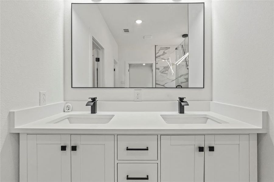 Full bathroom with a marble finish shower, double vanity, and a textured wall