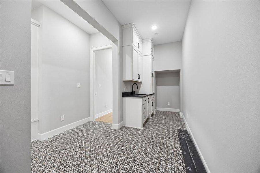 Kitchen with white cabinetry, dark countertops, and light colored carpet Kitchen with white cabinetry, dark countertops, and light colored carpet