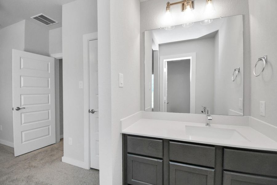 Secondary bath features tile flooring, bath/shower combo with tile surround, light stained wood cabinets, beautiful light countertop. Sample photo of completed home with similar floor plan. Actual colors and selections may vary.
