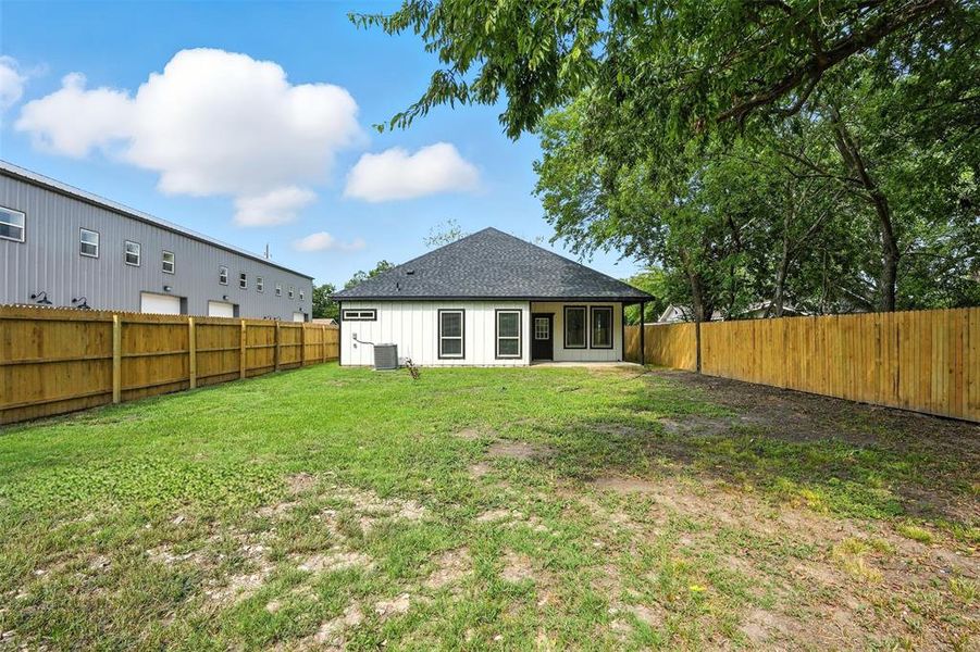 Rear view of house with a patio area, a fenced backyard, and a shingled roof