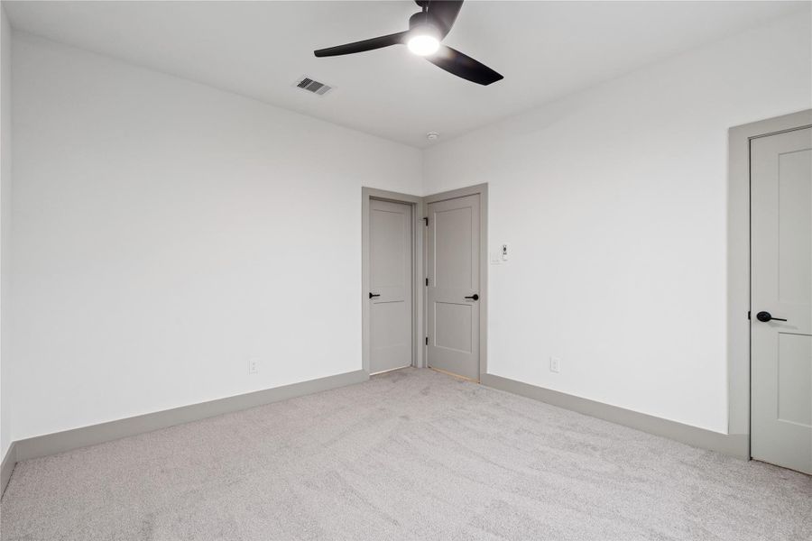 This secondary bedroom offers both comfort and versatility—featuring plush carpeting, neutral tones, generous closet space, and abundant natural light from oversized windows. A peaceful space ready to adapt to your lifestyle.